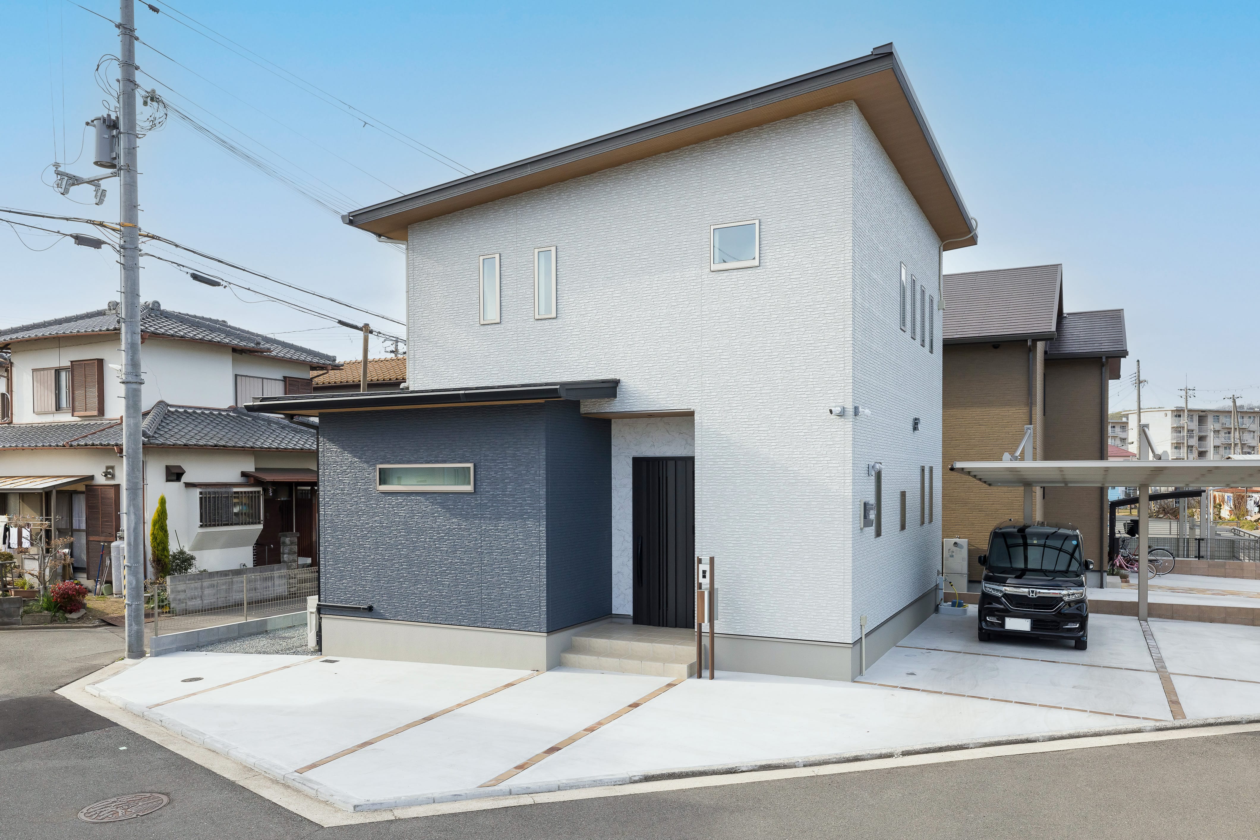 白とグレーを基調とした、シンプルでモダンな外観の二階建て住宅